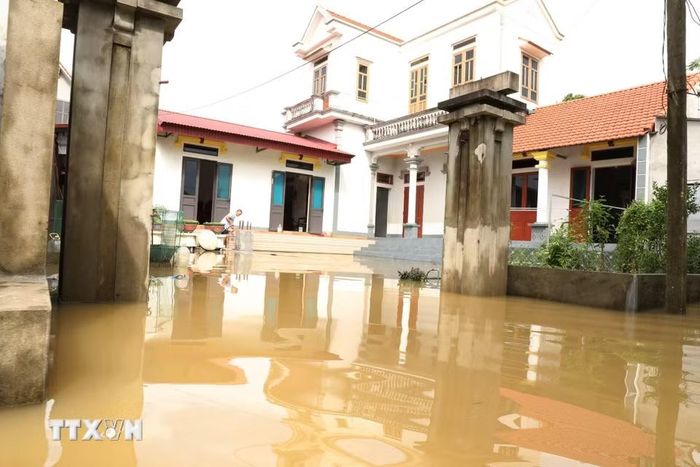 Một hộ dân thôn Gia Thủy, xã Gia Tường tranh thủ dọn dẹp ổn định cuộc sống khi nước rút. (Ảnh: Đức Phương/TTXVN)