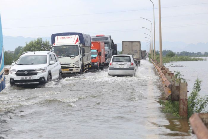 Mực nước sông dâng cao khiến nước tràn qua một số tuyến đường, ảnh hưởng đến việc đi lại của các phương tiện qua khu vực.