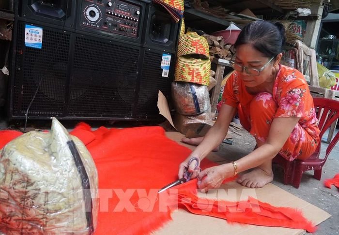 Cắt vải để trang trí cho đầu lân ở cở sở ông Cao Xuân Dũng, phường Phú Xuân, thành phố Huế. Ảnh: Nguyên Lý - TTXVN