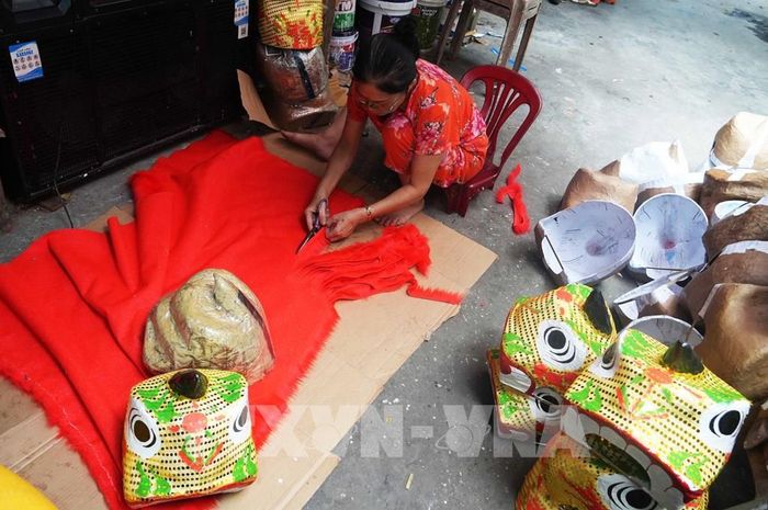 Cắt vải để trang trí cho đầu lân ở cở sở ông Cao Xuân Dũng, phường Phú Xuân, thành phố Huế. Ảnh: Nguyên Lý - TTXVN