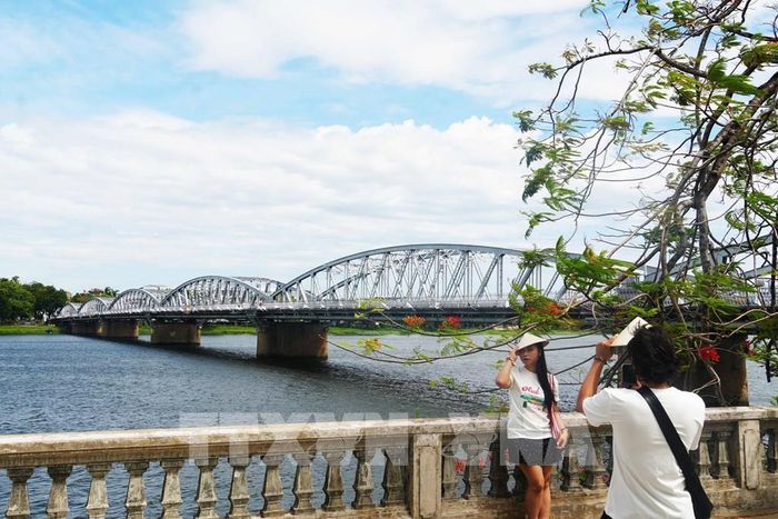 Du khách chụp ảnh bên cầu Trường Tiền. Ảnh: Nguyên Lý - TTXVN 