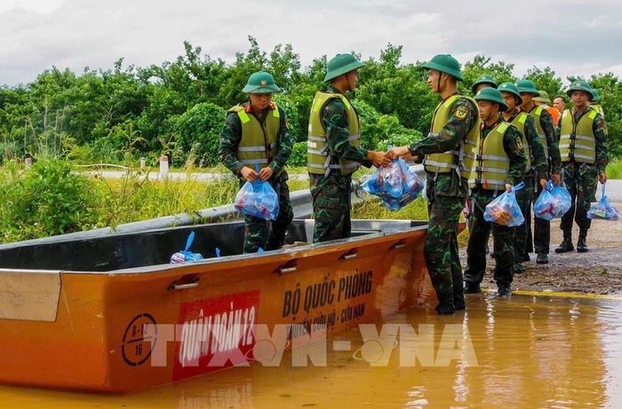 Cán bộ chiến sĩ Sư đoàn 325 vận chuyển nhu yếu phẩm cho người dân vùng bị cô lập ở xã Nam Dương. Ảnh: Danh Lam - TTXVN