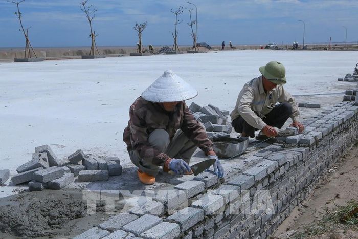 Công nhân xây dựng hạ tầng vỉa hè góp phần tạo diện mạo sạch đẹp, đồng bộ hơn cho không gian ven biển xã Giao Ninh. Ảnh: Công Luật - TTXVN