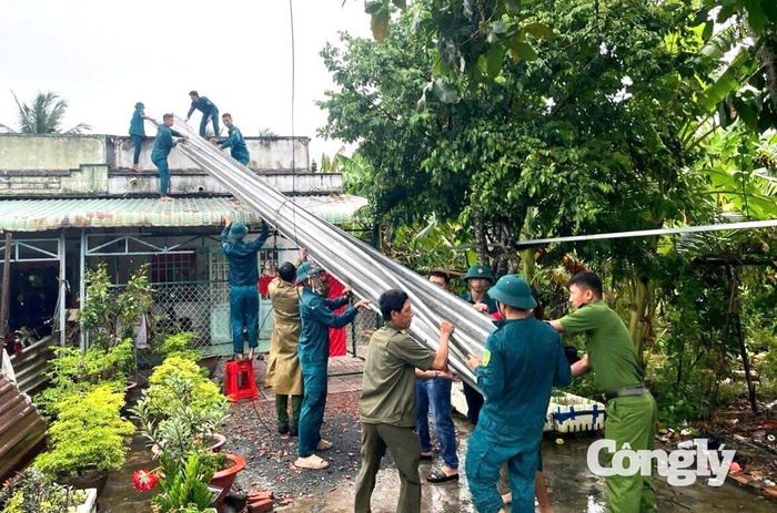 Cán bộ, chiến sĩ Công an xã hỗ trợ người dân trên địa bàn ấp Mỹ Lợi, xã Hiệp Hưng lợp lại mái tôn.