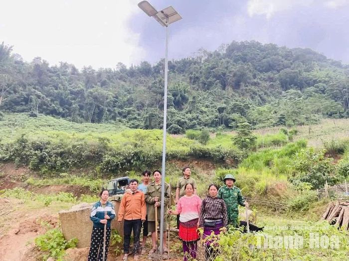 Cán bộ biên phòng và người dân vận chuyển thiết bị để lắp đặt hệ thống đèn năng lượng mặt trời trên các tuyến đường của bản.