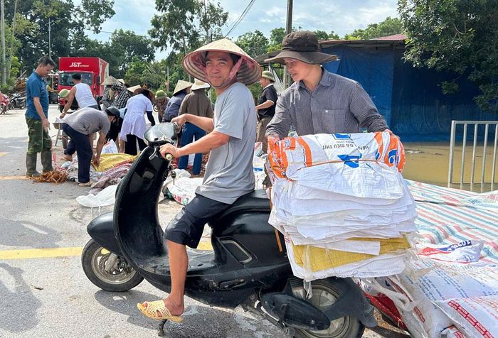  Trong gian khó vẫn sáng lên tinh thần đoàn kết.  Ảnh: Một người dân thôn Đông Sơn, xã Bố Hạ mang bao dứa của gia đình ủng hộ địa phương đắp đất ngăn nước lũ tràn bờ. 
