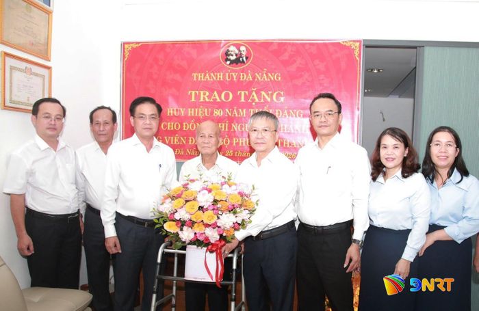 Chủ tịch HĐND thành phố Nguyễn Đức Dũng (thứ 4 từ phải qua) trao Huy hiệu 80 năm tuổi Đảng và tặng hoa chúc mừng đảng viên Nguyễn Thảnh. Ảnh: ĐẮC MẠNH