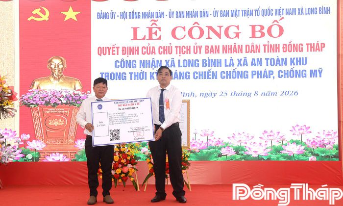 Đồng chí Châu Anh Vũ, Phó Chủ  tịch UBND xã Long Bình trao bảng tượng trưng bảo hiểm y tế cho đại diện hộ dân.  