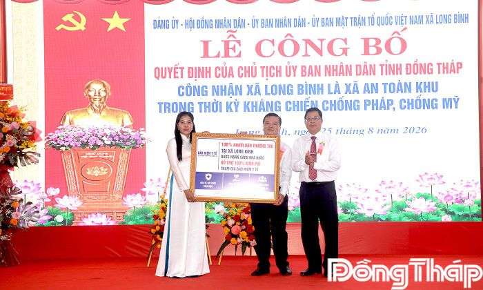 Đồng chí Trần Thanh Nguyên trao biểu trưng bảo hiểm y tế toàn dân xã Long Bình