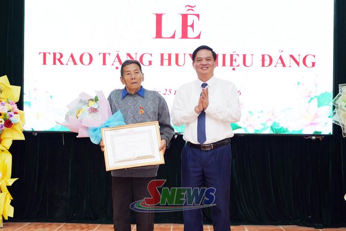 Đồng chí Nguyễn Mạnh Hùng trao tặng huy hiệu 60 năm tuổi Đảng và tặng hoa chúc mừng đảng viên Vừ Nhìa Dếnh.