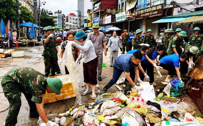 Lực lượng chức năng phối hợp các đoàn thể hỗ trợ người dân dọn dẹp rác thải. Ảnh: Thảo Anh
