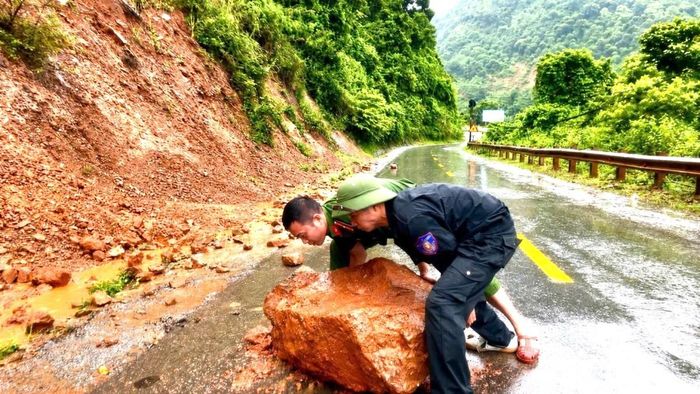 Lực lượng chức năng xã Nậm Cắn di chuyển các tảng đá, đảm bảo an toàn giao thông trên quốc lộ 7. (Ảnh: CTV)