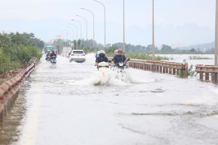 Tại xã Kiều Phú (Hà Nội), tỉnh lộ 421B ngập sâu do nước sông Tích dâng cao, nhiều phương tiện chật vật di chuyển qua vùng ngập. 