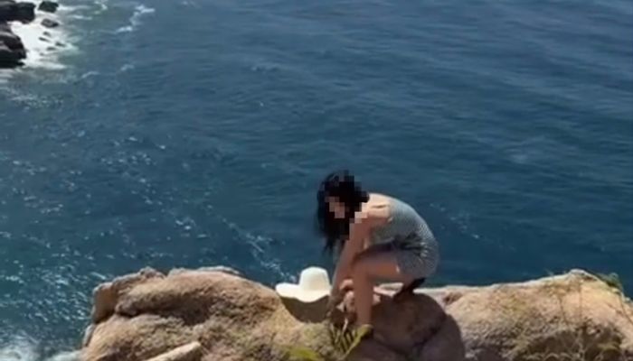 Nữ du khách leo trên vách đá cao (ảnh chụp màng hình)