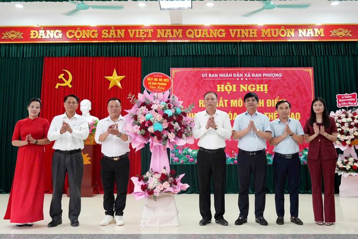 Bí thư Đảng ủy, Chủ tịch HĐND xã Đan Phượng Nguyễn Gia Hiển, Chủ tịch UBND xã Nguyễn Viết Đạt cùng các đồng chí lãnh đạo xã tặng hoa chúc mừng. Ảnh: Ngân Nguyễn