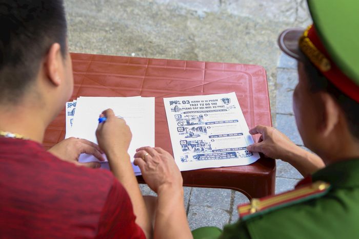 Công an phường Ngọc Hà tuyên truyền tới các hộ kinh doanh ký cam kết không sử dụng lòng đường, hè phố để kinh doanh, buôn bán, tổ chức trông, giữ xe trái quy định. Ảnh: Duy Khánh