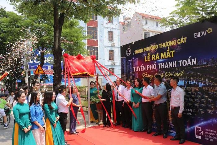 Các đại biểu thực hiện nghi thức gắn biển mô hình tuyến phố không dùng tiền mặt tại phố Kỳ Vũ, phường Thượng Cát. Ảnh: T. Cát