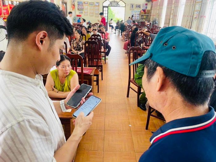 Chuyên viên Phòng Văn hoá - Xã hội xã Tam Hưng xuống từng thôn hướng dẫn người dân thực hiện các thủ tục trên môi trường số. Ảnh: Bình Minh 