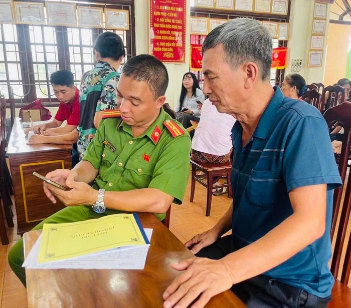 Công an xã Tam Hưng hỗ trợ người dân cài đặt ứng dụng báo cháy 114. Ảnh: Bình Minh 