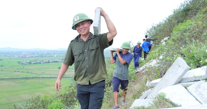 Những tấm bê tông nặng hơn 20kg được vận chuyển thủ công qua các đoạn dốc của núi Nhón. Ảnh: Hà Huệ.