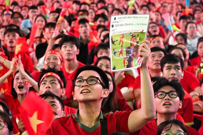  Việt Nam bước vào trận chung kết lượt về với lợi thế lớn sau khi thắng Thái Lan 2-0 ở trận lượt đi trên sân Rajamangala. Song hành trình bảo vệ ngôi vương không dễ dàng. Từ những phút đầu khi Thái Lan mở tỷ số, đám đông tại các điểm xem bóng đá có lúc lặng đi. Lợi thế 2-0 từ lượt đi vẫn còn, nhưng bàn thua khiến nhiều người bắt đầu lo lắng. Không khí chỉ thực sự bùng lên khi Việt Nam có bàn gỡ trong hiệp hai. Những tiếng reo hò lập tức át tiếng bình luận từ màn hình, người hâm mộ vẫy cờ, ôm nhau và hô vang tên đội tuyển. Mỗi pha bóng nguy hiểm sau đó đều kéo theo những tiếng hò hét. Ảnh: Hoài Bảo. 