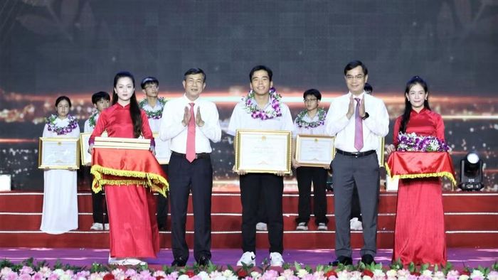 Đại diện lãnh đạo Ủy ban nhân dân tỉnh Nghệ An và Giám đốc Sở Giáo dục và Đào tạo tặng hoa và trao Bằng khen của Ủy ban nhân dân tỉnh cho các em học sinh đạt điểm cao trong kỳ thi tốt nghiệp trung học phổ thông năm 2026. (Ảnh: TTH)