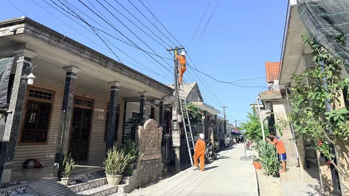 Công nhân Điện lực Phú Vang, Công ty Điện lực Huế tiến hành các biện pháp bảo đảm khoảng cách an toàn cho công tơ, đường dây tại khu vực có nguy cơ ngập úng. (Ảnh: LÊ CHI)