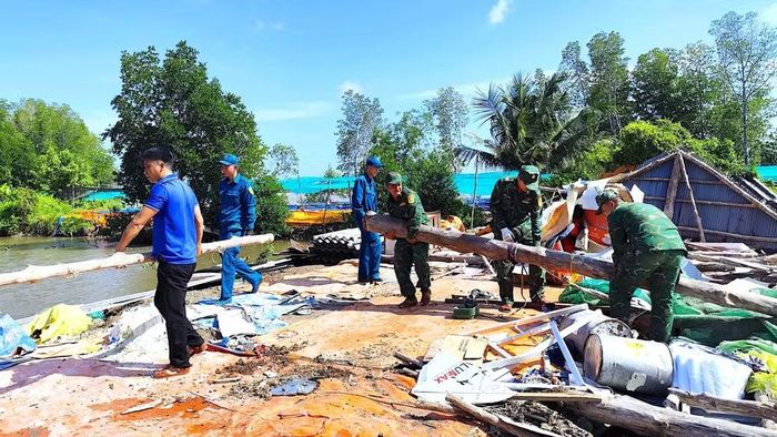 Biên phòng Đất Mũi cùng lực lượng tại chỗ vận chuyển cột nhà bị sập đưa ra vị trí tập kết. (Ảnh: Hoàng Tá)