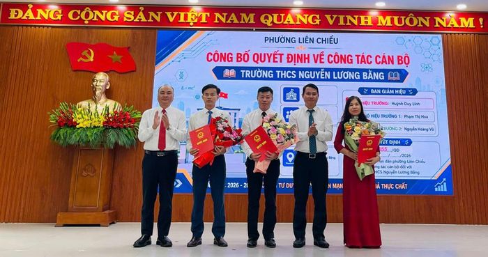 Chủ tịch UBND phường Liên Chiểu Trần Công Nguyên trao quyết định và tặng hoa chúc mừng đội ngũ cán bộ quản lý Trường THCS Nguyễn Lương Bằng sau sắp xếp.