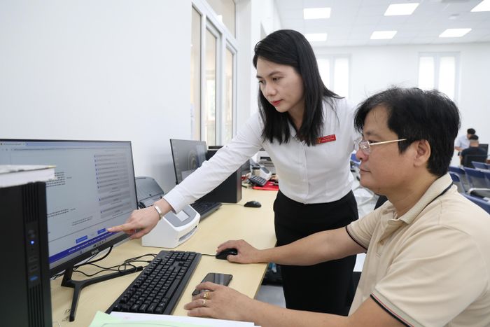  Cán bộ Trung tâm Phục vụ hành chính công TPHCM hướng dẫn thủ tục trực tuyến cho người dân. ẢNH: LÊ THOA 