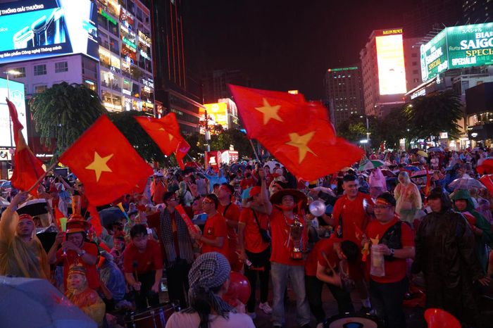 Những lá cờ đỏ sao vàng tung bay trong màn mưa, tạo nên bầu không khí cuồng nhiệt cùng quả bóng lăn