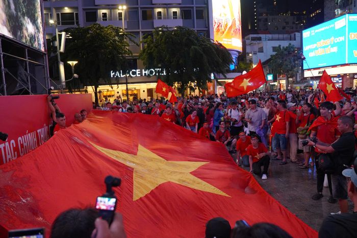 Hàng trăm cổ động viên cùng nhau giương lá cờ đỏ sao vàng khổng lồ, tạo nên khoảnh khắc ấn tượng tại phố đi bộ Nguyễn Huệ