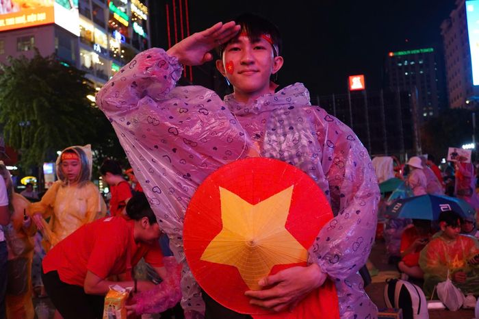  Người hâm mộ mặc áo mưa, mang theo nón lá in cờ Tổ quốc xuống đường cổ vũ đội tuyển Việt Nam vào chiều trước khi diễn ra trận đấu 