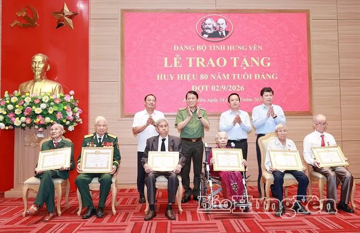 Đại tướng Lương Tam Quang, Ủy viên Bộ Chính trị, Bộ trưởng Bộ Công an và các đồng chí Thường trực Tỉnh ủy chụp ảnh lưu niệm cùng các đảng viên được nhận Huy hiệu 80 năm tuổi Đảng. Ảnh: Báo Hưng Yên.