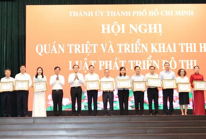 Bí thư Thành ủy TPHCM Trần Lưu Quang và Chủ tịch HĐND TPHCM Võ Văn Minh trao bằng khen tuyên dương các đơn vị có đóng góp tích cực trong xây dựng Luật Phát triển đô thị.