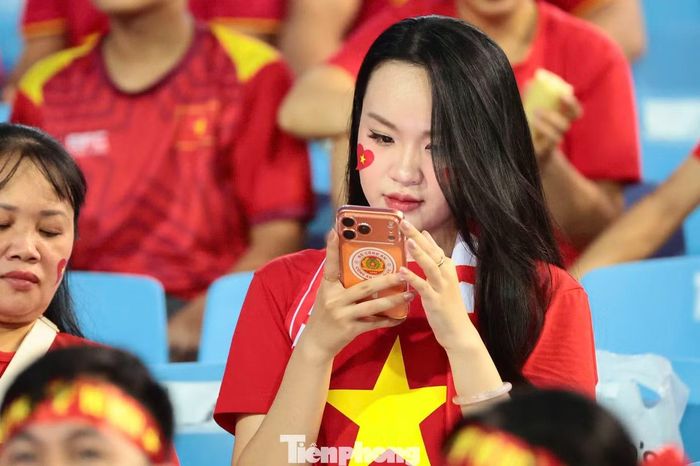 Một nữ cổ động viên mặc áo cờ đỏ sao vàng, dán trái tim hình quốc kỳ lên má có mặt trên khán đài sân Mỹ Đình. Người hâm mộ kỳ vọng đội tuyển Việt Nam bảo vệ lợi thế đã tạo ra sau chiến thắng 2-0 ở trận chung kết lượt đi trên sân Rajamangala.