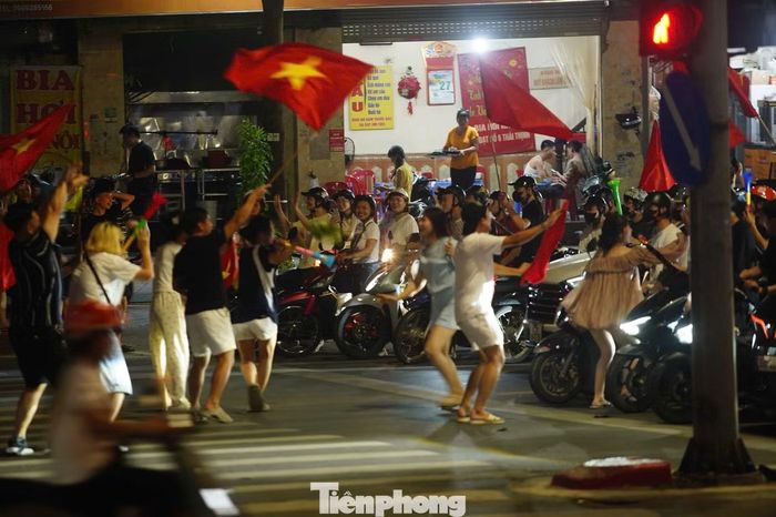 Trong lúc đoàn xe chờ đèn đỏ, đám đông đi bộ tranh thủ tràn xuống đường ăn mừng.