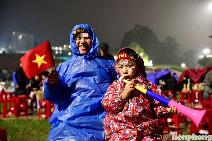Hai bà cháu đội mưa có mặt tại Quảng trường Lâm Viên để cổ vũ đội tuyển Việt Nam.