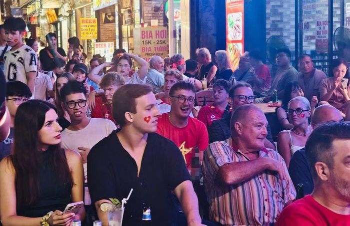 Giữa không gian náo nhiệt của phố đêm, những tiếng hô vang hòa cùng tiếng nhạc, tiếng cười tạo nên khung cảnh đặc biệt, nơi du khách quốc tế dễ dàng hòa vào dòng người hâm mộ như những cổ động viên Việt Nam thực thụ. Ảnh: Thanh Hà.