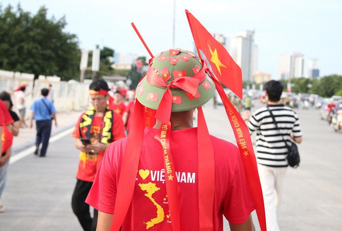 Một CĐV mang theo mũ cối dán nhiều cờ Việt Nam vào sân.