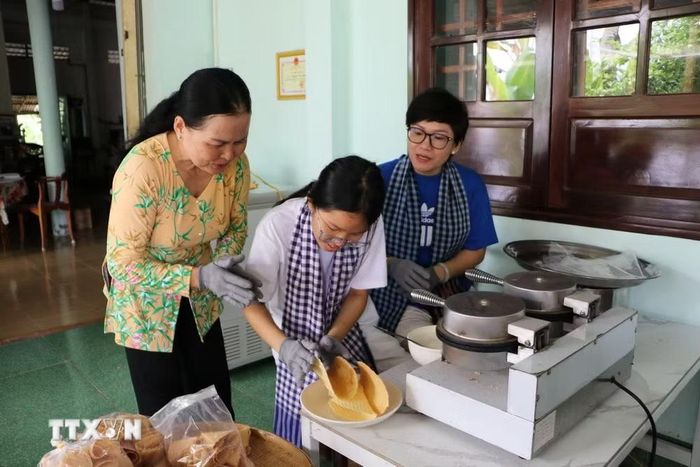 Du khách trải nghiệm làm bánh kẹp xoài. (Ảnh: Hồng Thái/TTXVN)