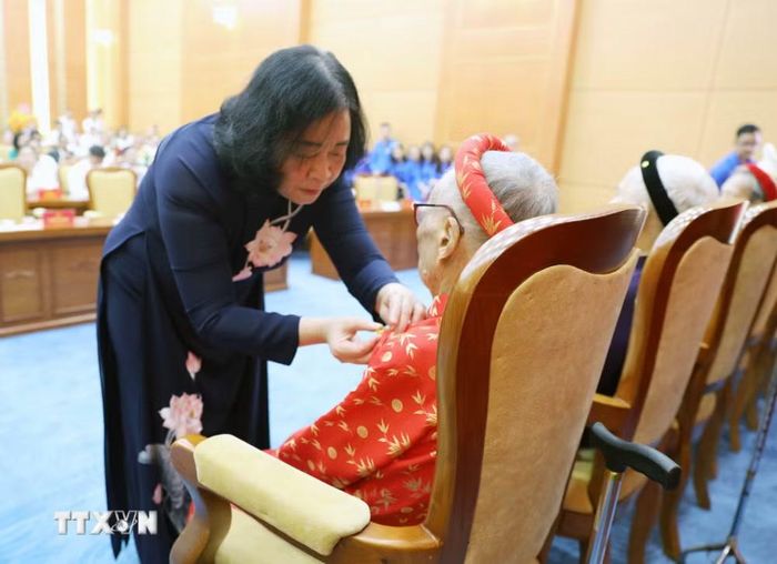 Ủy viên Bộ Chính trị, Chủ tịch Ủy ban Trung ương Mặt trận Tổ quốc Việt Nam Bùi Thị Minh Hoài gắn Huy hiệu Đảng và trao Quyết định cho các đảng viên lão thành tại buổi lễ. (Ảnh: Tạ Toàn/TTXVN)