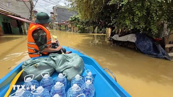 Lực lượng quân đội vận chuyển nước uống tới khu vực bị mưa lũ cô lập. (Ảnh: Quang Duy/TTXVN)