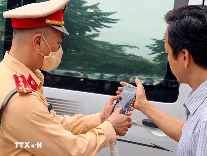 Cảnh sát giao thông kiểm tra thông tin liên quan đến hành trình và hoạt động của phương tiện kinh doanh vận tải. (Ảnh: Trung Nguyên/TTXVN)