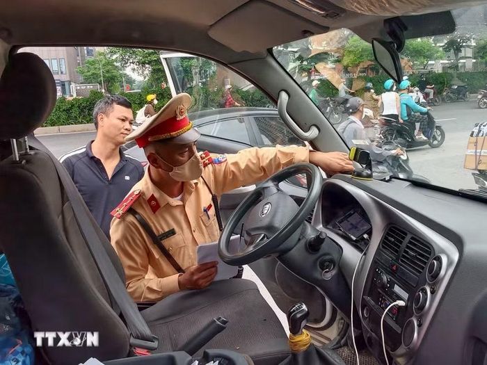 Lực lượng Cảnh sát giao thông kiểm tra thiết bị giám sát hành trình lắp trên phương tiện kinh doanh vận tải. (Ảnh: Trung Nguyên/TTXVN)