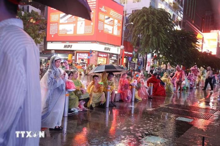 Người hâm mộ Thành phố Hồ Chí Minh đội mưa tập trung tại phố đi bộ Nguyễn Huệ trước trận chung kết lượt về. (Ảnh: Hồng Đạt/TTXVN)