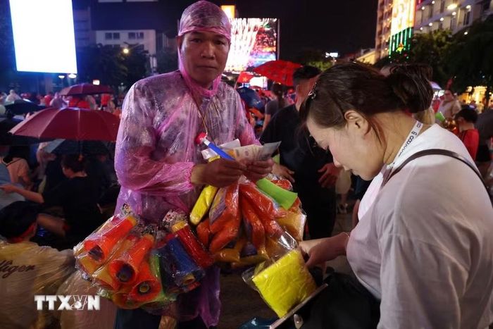 Áo mưa và kèn đắt hàng trước trận chung kết lượt về Asian Cup giữa Việt Nam và Thái Lan trên phố đi bộ Nguyễn Huệ. (Ảnh: Hồng Đạt/TTXVN)
