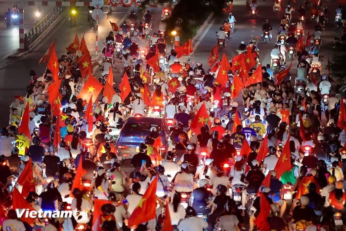 Dòng phương tiện nhích từng mét một trong sự hân hoan. Không có sự gắt gỏng hay mệt mỏi vì tắc đường, thay vào đó là những cái đập tay giòn giã, những lời chúc mừng của những người xa lạ chung một tình yêu bóng đá. (Ảnh: Hoài Nam/Vietnam+)
