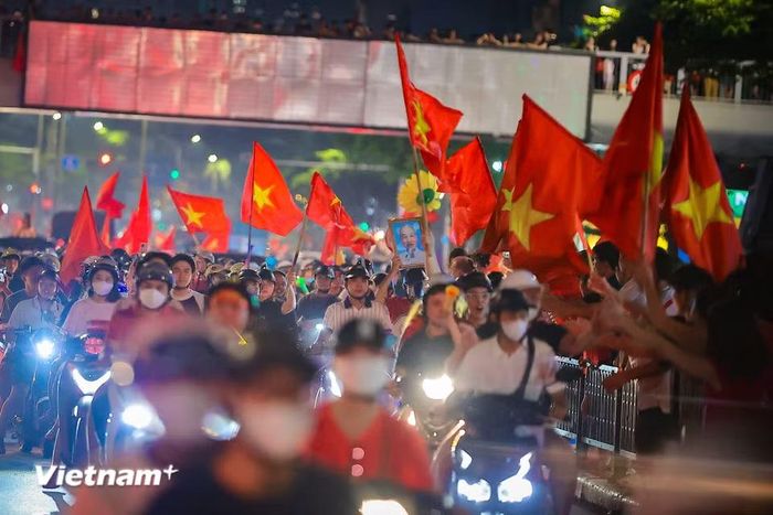 Hình ảnh Bác Hồ cùng lá cờ đỏ sao vàng xuất hiện trên đường phố trong đêm chiến thắng của Đội tuyển bóng đá Việt Nam. (Ảnh: Hoài Nam/Vietnam+)