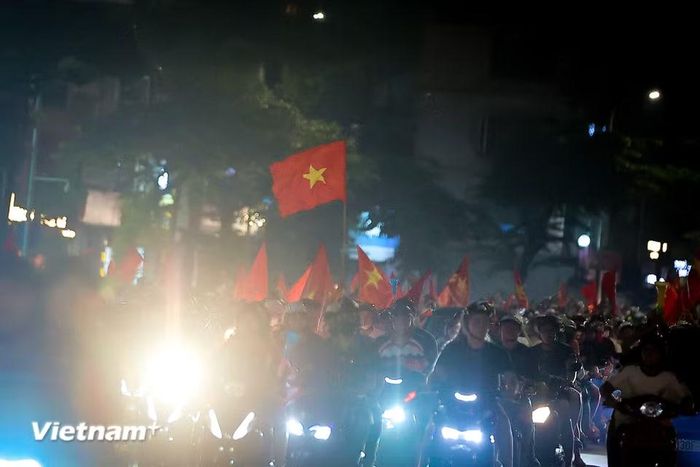 Càng về khuya, không khí ăn mừng càng trở nên thăng hoa, những lá đại kỳ tung bay kiêu hãnh trong ánh sáng rực rỡ. (Ảnh: Hoài Nam/Vietnam+)